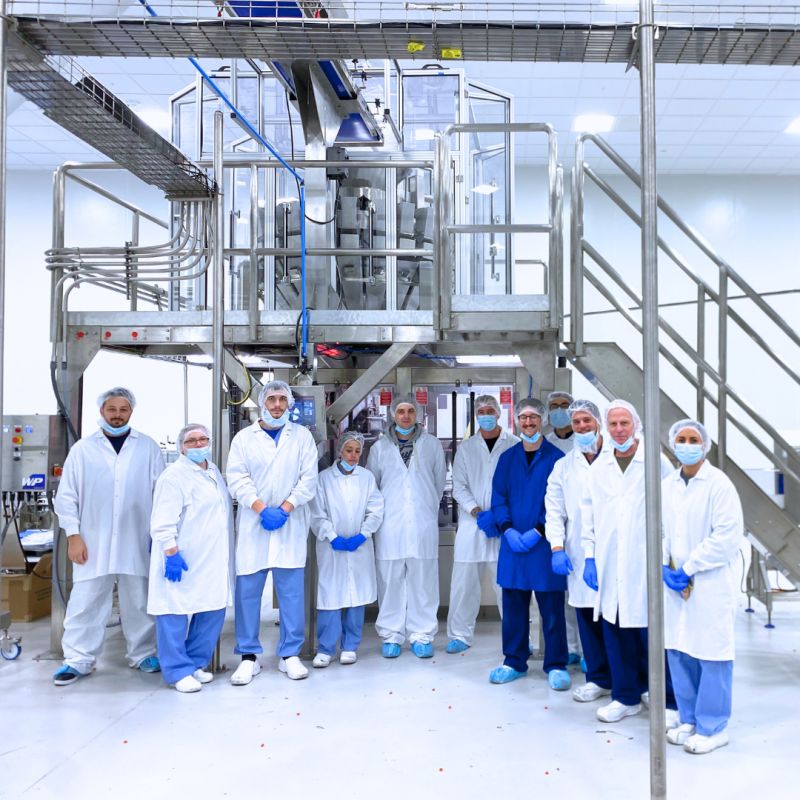 customers smiling in front of automated gummy container filling machine